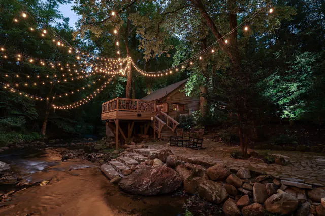 Riverfront Hideaway cabin deck over the Middle Saluda River under string lights in Marietta, SC